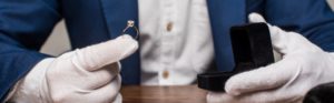 jewelry appraiser holding ring with gemstone and box on table