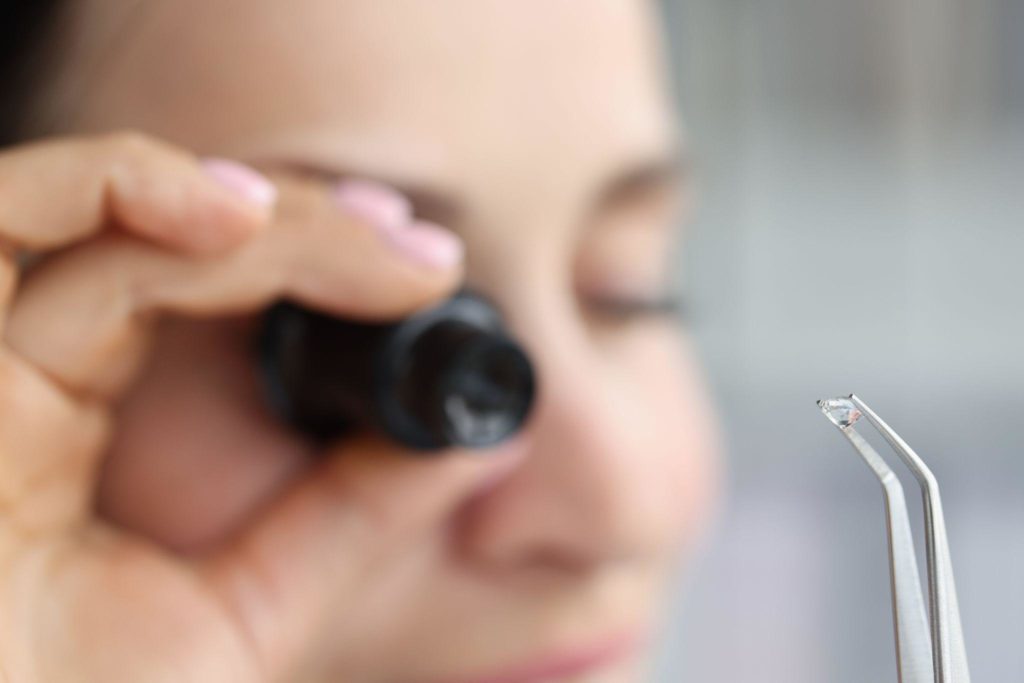 Jeweller examine polished diamond through magnifying glass