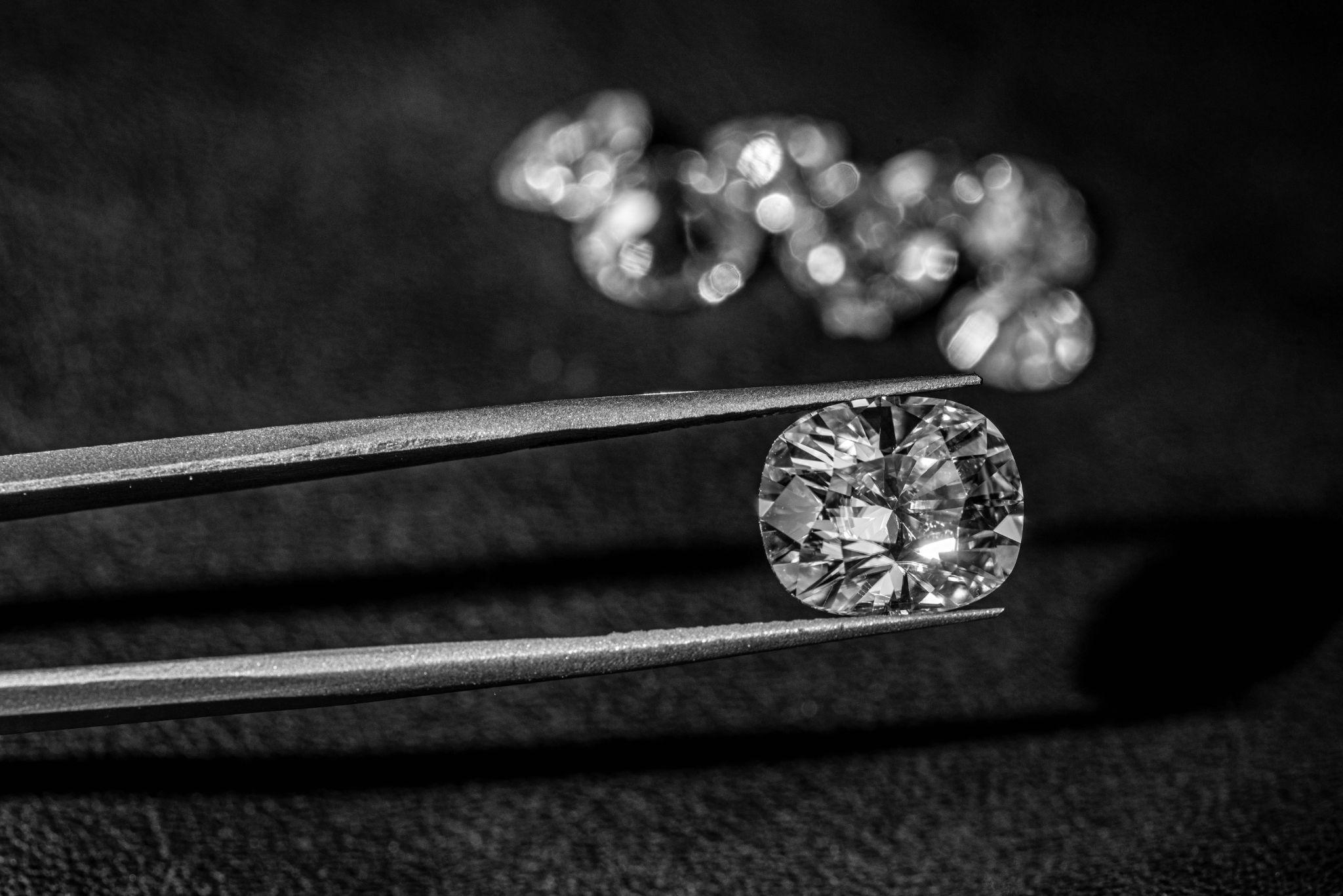 Diamond in tweezers on black background.