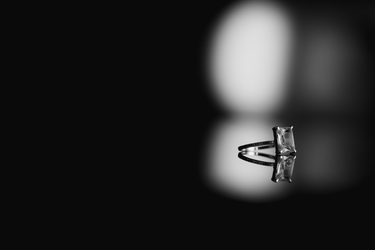 Single diamond engagement ring on black background.